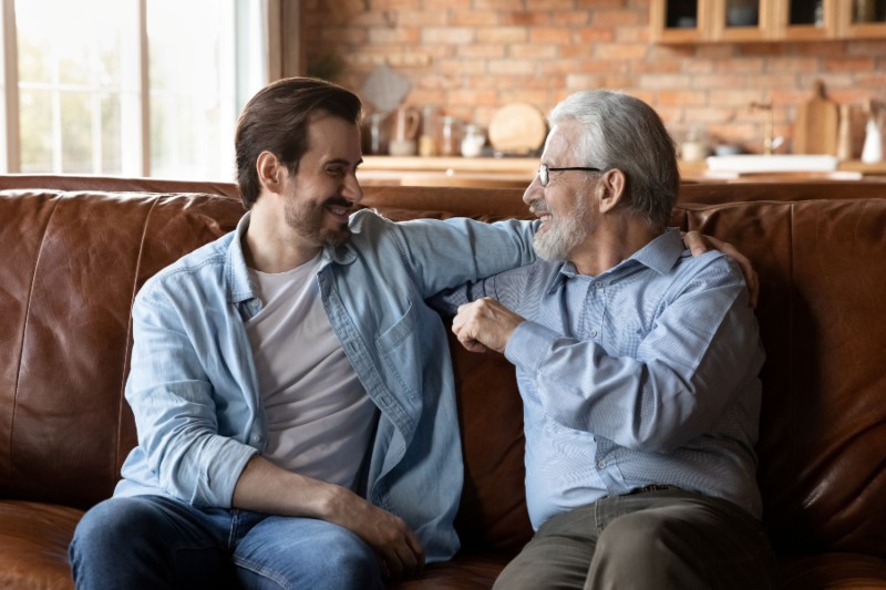 Two men sitting closely on a couch, engaged in conversation, Naples FL